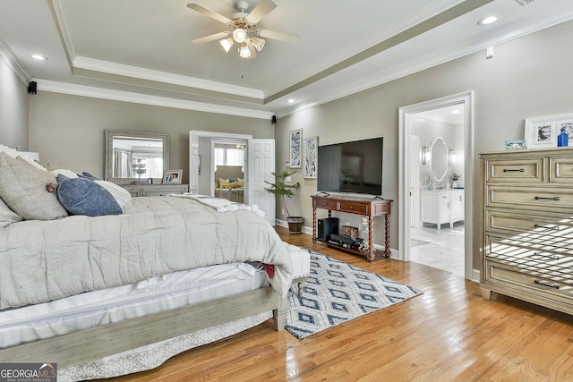 bedroom with a raised ceiling, ensuite bathroom, hardwood / wood-style floors, and ceiling fan