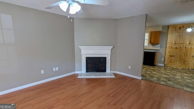 unfurnished living room with ceiling fan, light hardwood / wood-style floors, and a textured ceiling