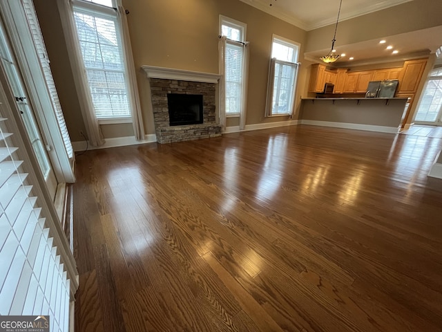 unfurnished living room featuring a stone fireplace, dark wood-type flooring, and ornamental molding