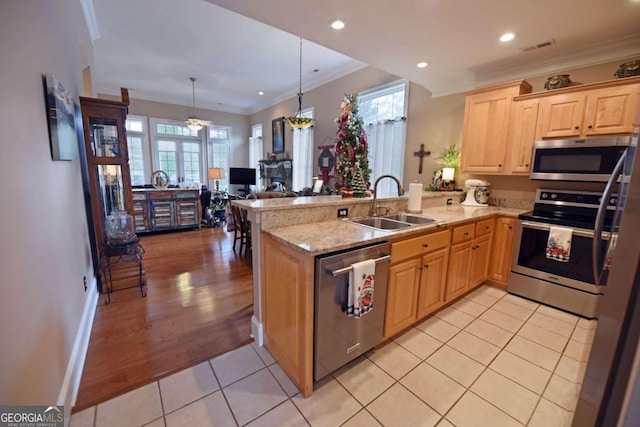 kitchen with sink, hanging light fixtures, stainless steel appliances, ornamental molding, and kitchen peninsula