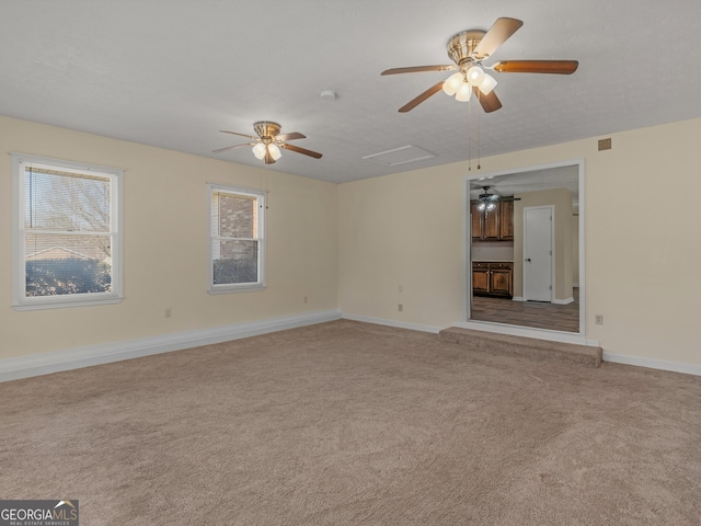 unfurnished living room with attic access, visible vents, baseboards, a ceiling fan, and light colored carpet