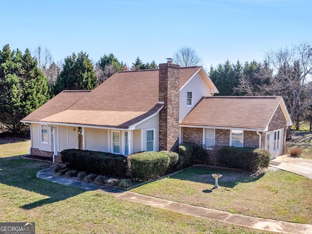 view of front of home with an attached garage, brick siding, a chimney, and a front yard