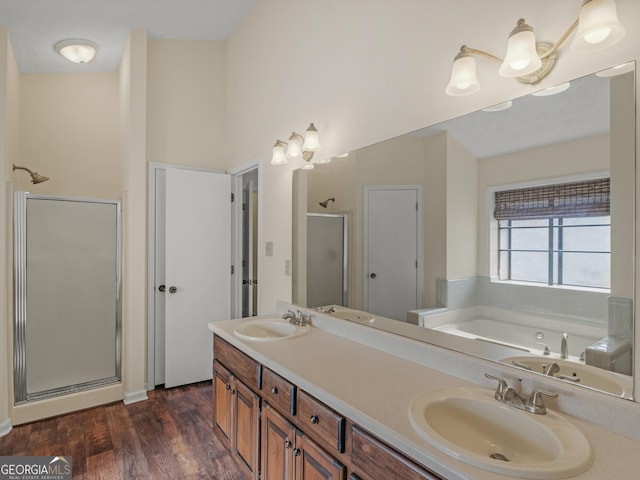 full bathroom with double vanity, wood finished floors, a sink, and a shower stall