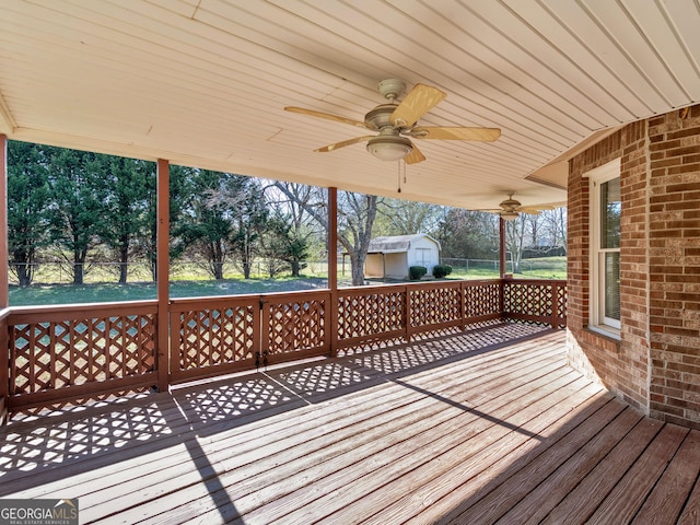 wooden terrace with a ceiling fan, a yard, an outdoor structure, and a storage unit