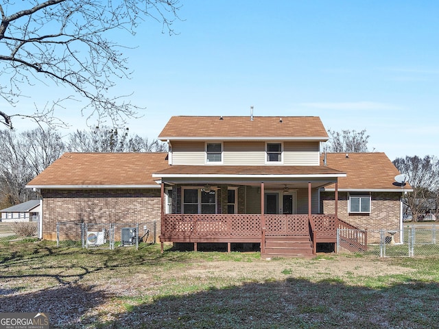 rear view of property with ceiling fan, brick siding, a lawn, and fence