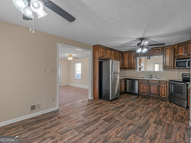 kitchen featuring appliances with stainless steel finishes, dark wood-style flooring, light countertops, and visible vents