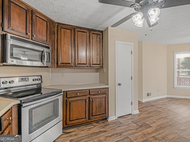 kitchen with a textured ceiling, wood finished floors, visible vents, light countertops, and appliances with stainless steel finishes