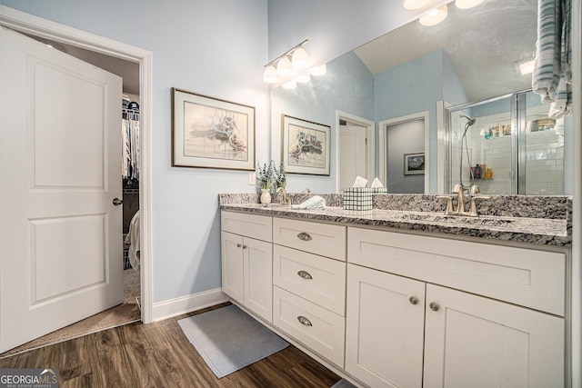 bathroom with hardwood / wood-style floors, a shower with door, and vanity