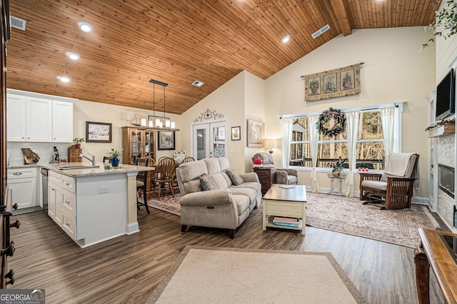 living room featuring wood ceiling, sink, dark hardwood / wood-style floors, high vaulted ceiling, and a tiled fireplace