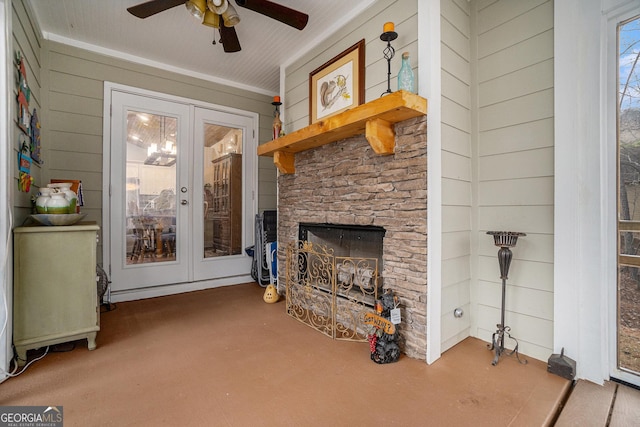 living room with ceiling fan, french doors, a stone fireplace, and wooden walls