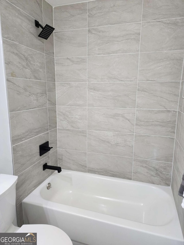 bathroom featuring tiled shower / bath combo and toilet