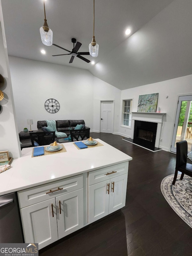 kitchen featuring vaulted ceiling, decorative light fixtures, white cabinetry, and dark wood-type flooring