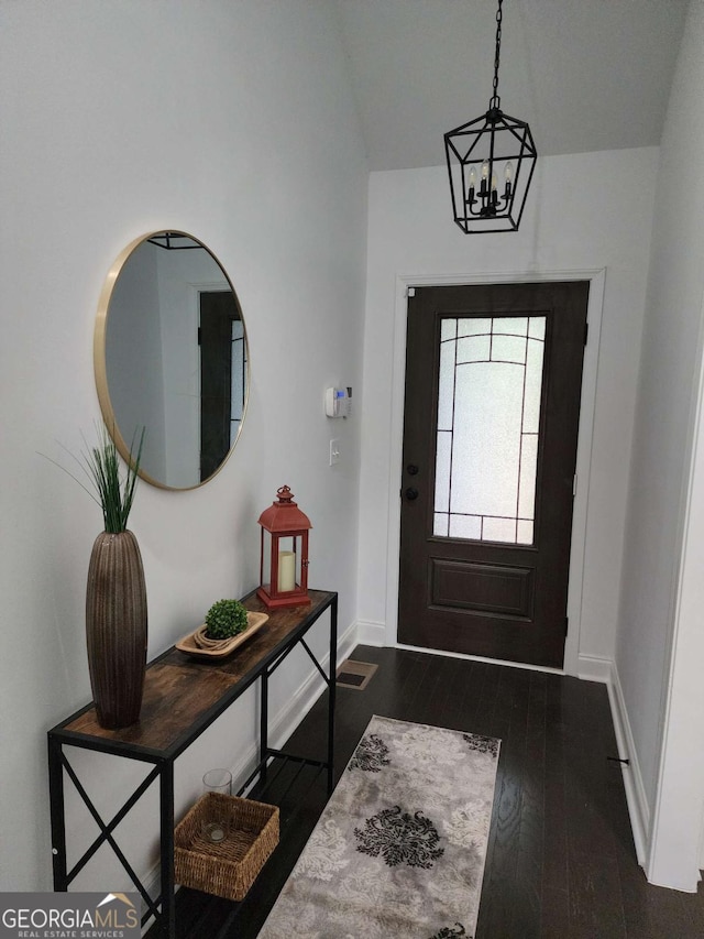 entryway with lofted ceiling, dark hardwood / wood-style flooring, and a notable chandelier