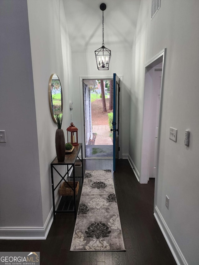 foyer entrance featuring dark hardwood / wood-style floors and an inviting chandelier