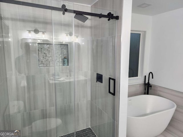 bathroom featuring shower with separate bathtub and tile walls