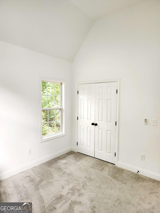 carpeted empty room featuring vaulted ceiling