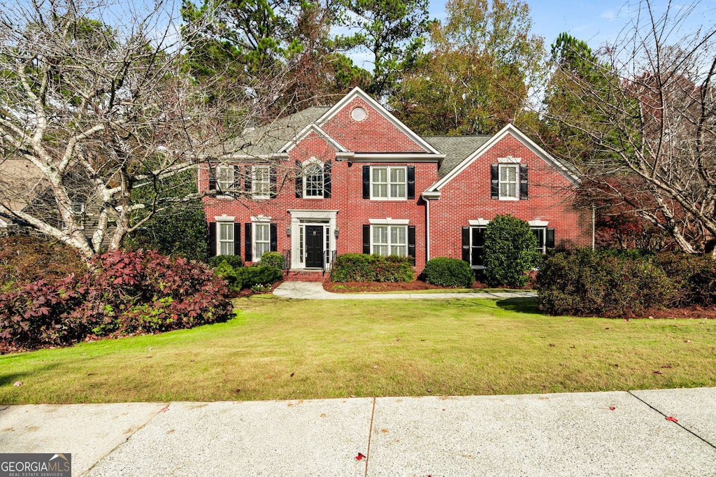 colonial inspired home featuring a front lawn