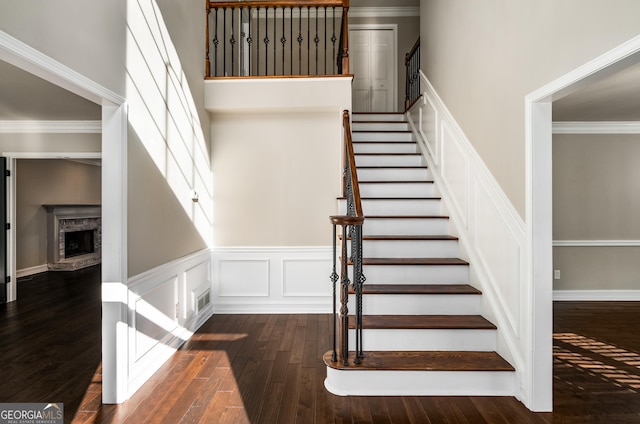 stairway featuring hardwood / wood-style flooring, crown molding, and a high ceiling