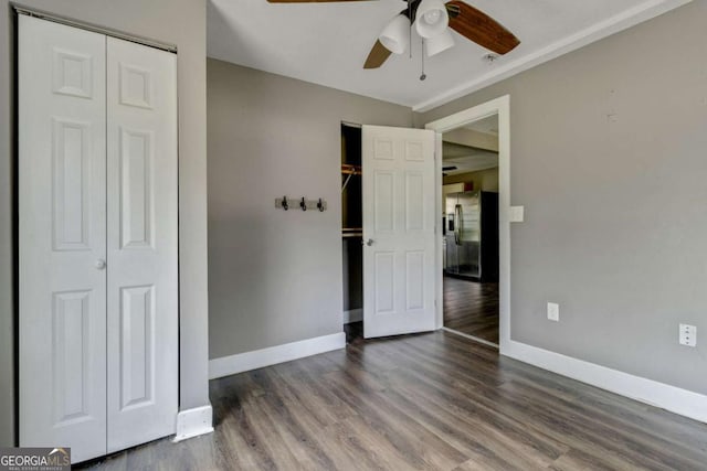 unfurnished bedroom with dark hardwood / wood-style flooring, a closet, ceiling fan, and fridge with ice dispenser