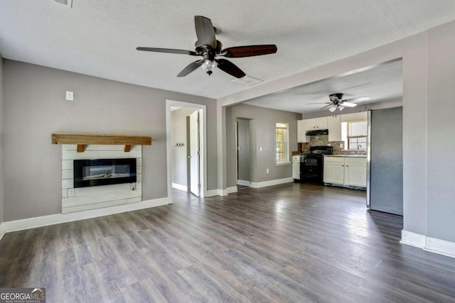 unfurnished living room featuring a textured ceiling, ceiling fan, sink, and dark wood-type flooring