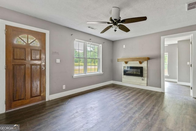 unfurnished living room with dark hardwood / wood-style flooring, a textured ceiling, and ceiling fan