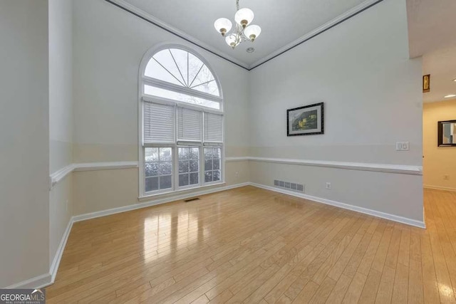 unfurnished room with a notable chandelier and light hardwood / wood-style flooring