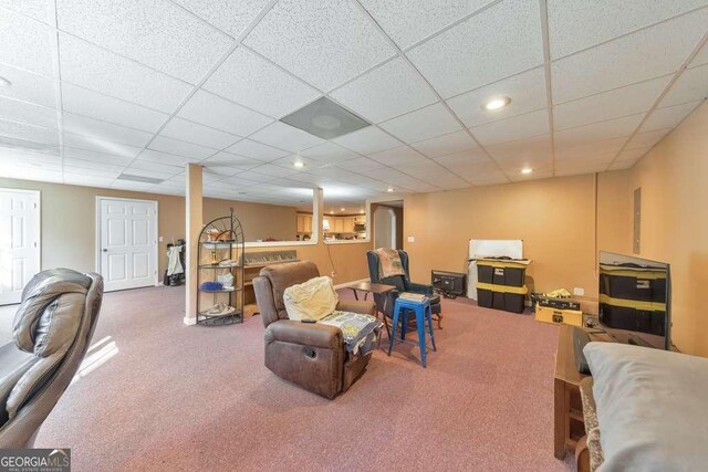 living room featuring carpet flooring and a drop ceiling