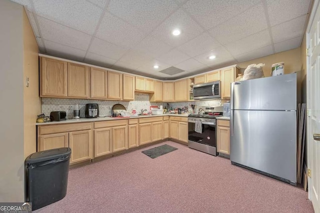 kitchen featuring a paneled ceiling, appliances with stainless steel finishes, backsplash, carpet flooring, and light brown cabinetry