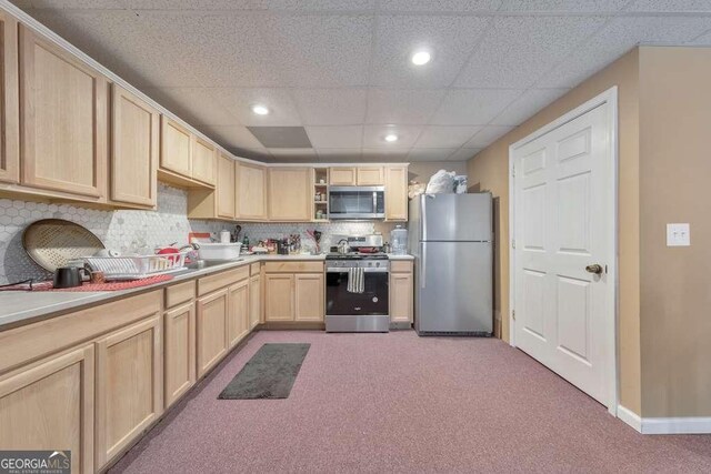 kitchen featuring light brown cabinetry, sink, light colored carpet, stainless steel appliances, and backsplash