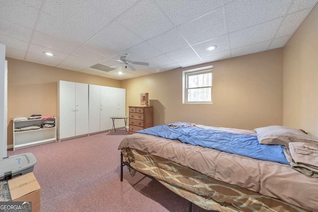 carpeted bedroom featuring a drop ceiling, ceiling fan, and a closet