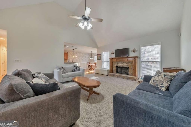 living room with ceiling fan, a stone fireplace, light carpet, and high vaulted ceiling