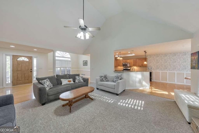 living room featuring high vaulted ceiling, sink, and light hardwood / wood-style floors