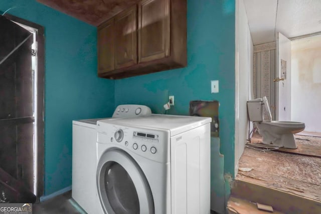 clothes washing area with cabinets and washing machine and dryer