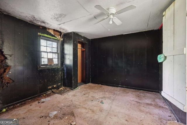 spare room featuring ceiling fan and wood walls