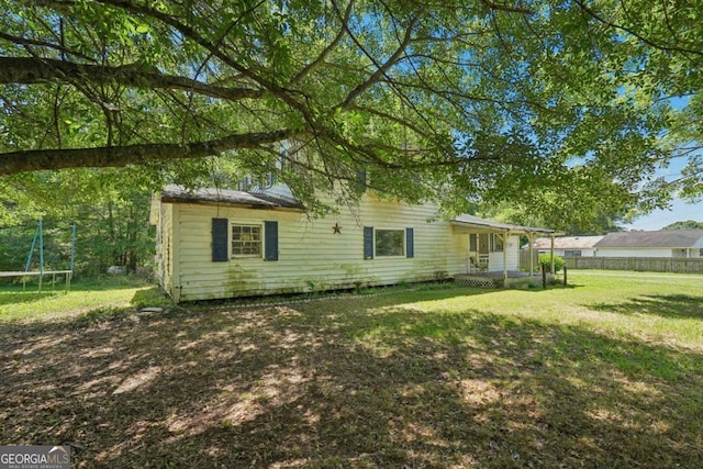 rear view of house with a lawn and a trampoline