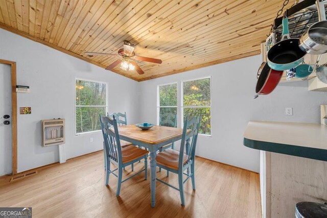 dining room with light hardwood / wood-style floors, a healthy amount of sunlight, lofted ceiling, and heating unit