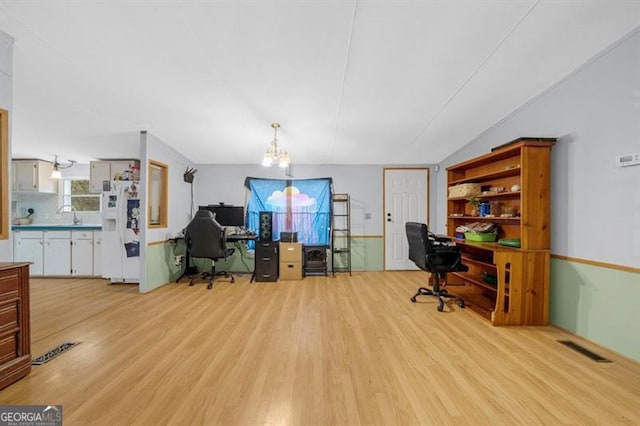 office with light hardwood / wood-style floors and a notable chandelier