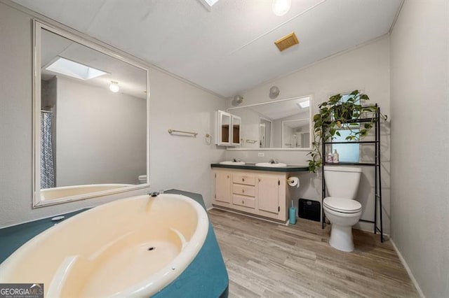 bathroom with hardwood / wood-style flooring, vanity, toilet, and lofted ceiling with skylight