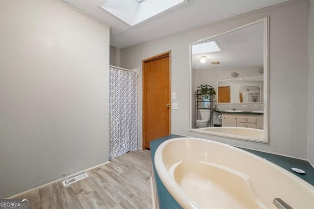 bathroom featuring walk in shower, a skylight, toilet, and hardwood / wood-style flooring