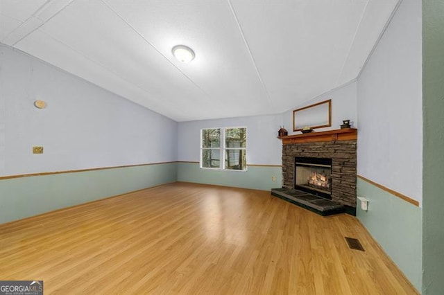 unfurnished living room with a fireplace, light hardwood / wood-style floors, and vaulted ceiling