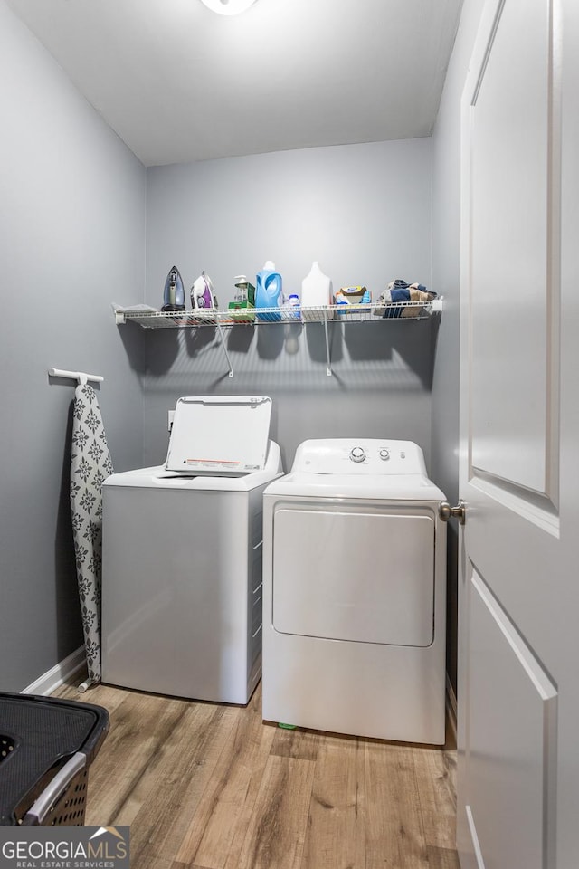 clothes washing area with washing machine and dryer and light hardwood / wood-style flooring