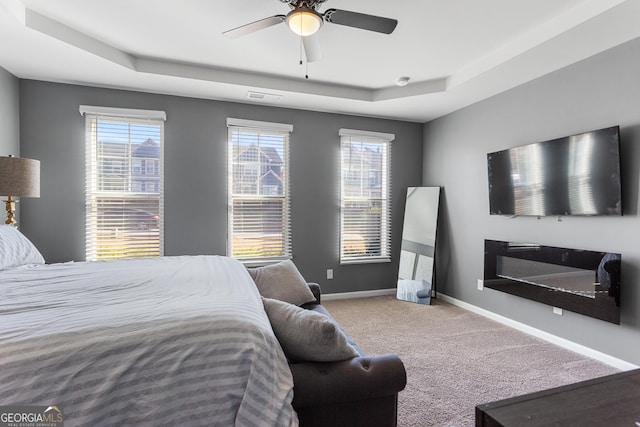 bedroom featuring carpet, a raised ceiling, and ceiling fan