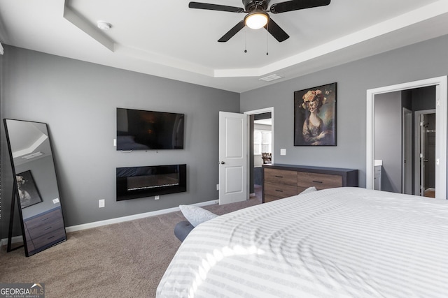 bedroom featuring ceiling fan, carpet floors, and a tray ceiling