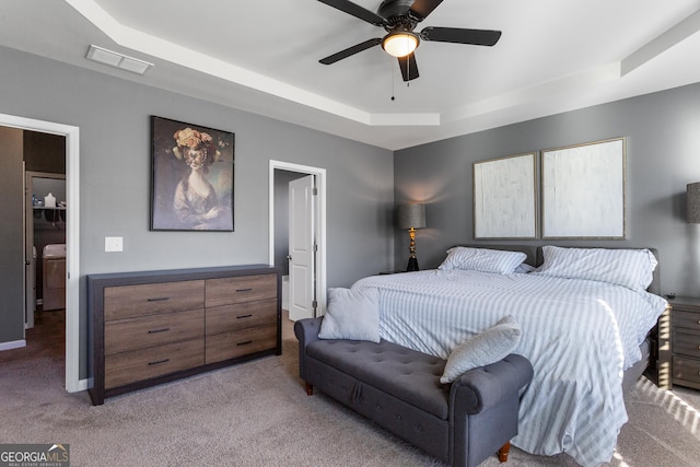 bedroom featuring light carpet, a raised ceiling, and ceiling fan