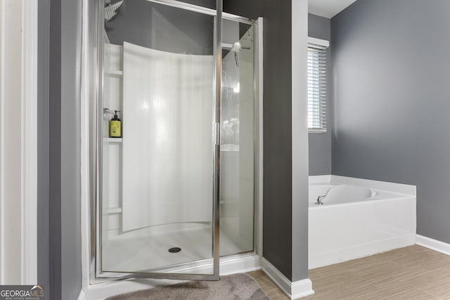 bathroom with wood-type flooring and shower with separate bathtub