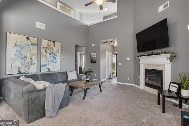 carpeted living room featuring ceiling fan and a towering ceiling