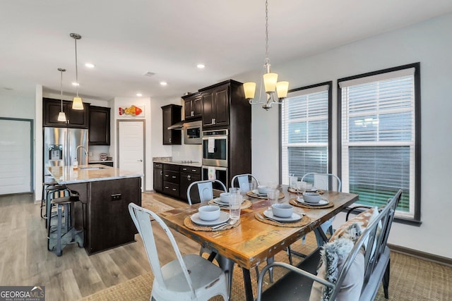 dining area featuring sink, light hardwood / wood-style floors, and an inviting chandelier