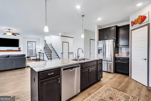 kitchen featuring pendant lighting, a kitchen island with sink, sink, light hardwood / wood-style flooring, and stainless steel appliances