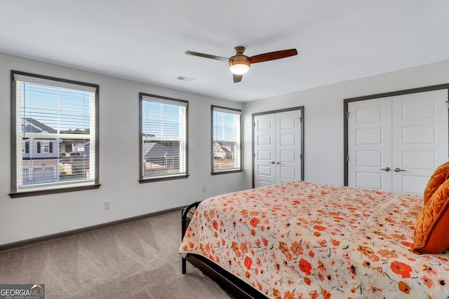 bedroom with carpet flooring, multiple closets, and ceiling fan