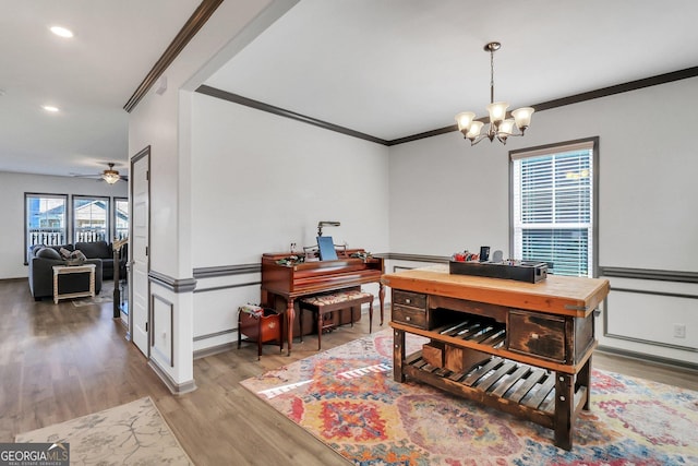 home office with ceiling fan with notable chandelier, light wood-type flooring, and crown molding